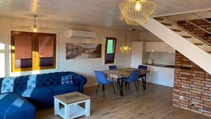 Ein modernes Interieur mit einer Couch, einem Esstisch, Stühlen und einer Treppe.