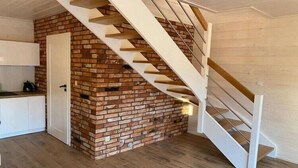 Eine Treppe mit einer Ziegelwand, Holzstufen und einer weißen Tür.