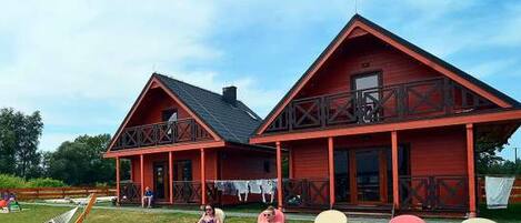 A red wooden building with a porch and two visible windows.