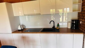 A compact kitchen with a sink, a kettle, and a coffee maker. - Air-conditioned holiday homes with swimming pool (Mielno)