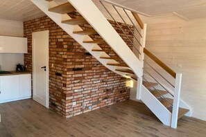 A modern kitchen with white cabinets, a brick accent wall, and a wooden staircase. - Air-conditioned holiday homes with swimming pool (Mielno)
