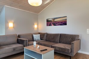 Una sala de estar moderna con un sofá modular, una mesa de centro y un cuadro colgado en la pared.