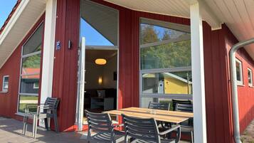A red building with a table and chairs outside, a door leading inside, and a clear sky.
