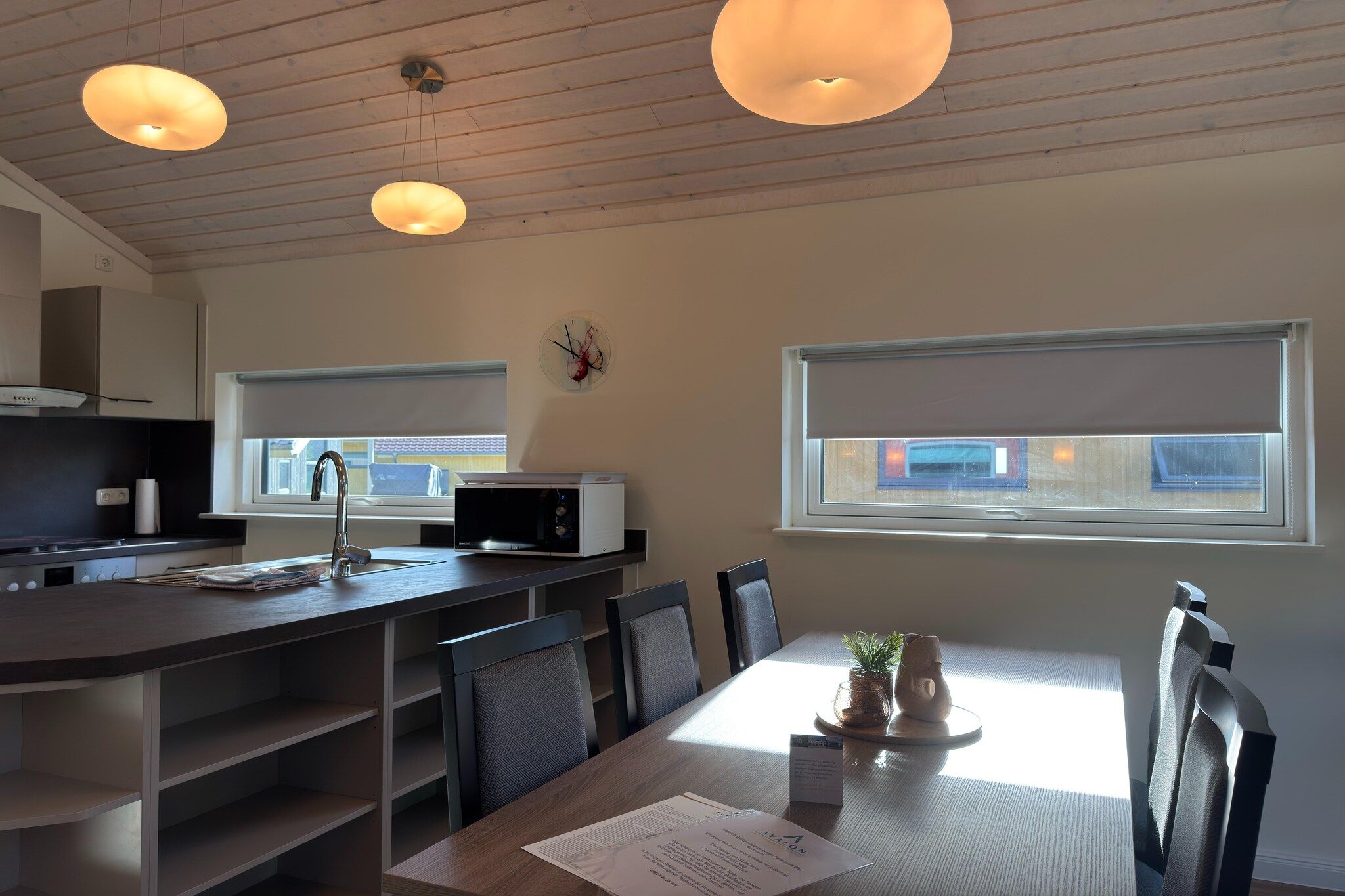 A modern kitchen with a microwave, sink, and dining area with chairs and a table.