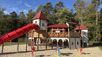 A playground with a red slide and wooden play structures.