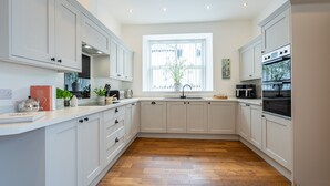 Een moderne keuken met witte kasten, een houten vloer en een raam met uitzicht.