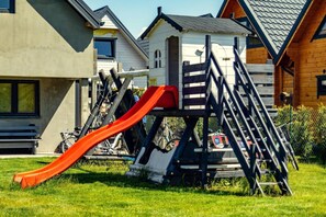 A playground with a slide and climbing structure, surrounded by houses.