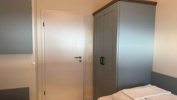 Une chambre à coucher avec un lit, une armoire et une porte.