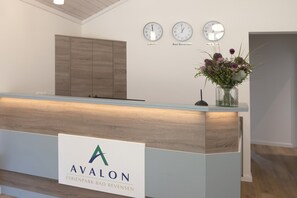 Ein Empfangsschalter mit einem Logo, Uhren, die verschiedene Zeitzonen anzeigen, und eine Vase mit Blumen.