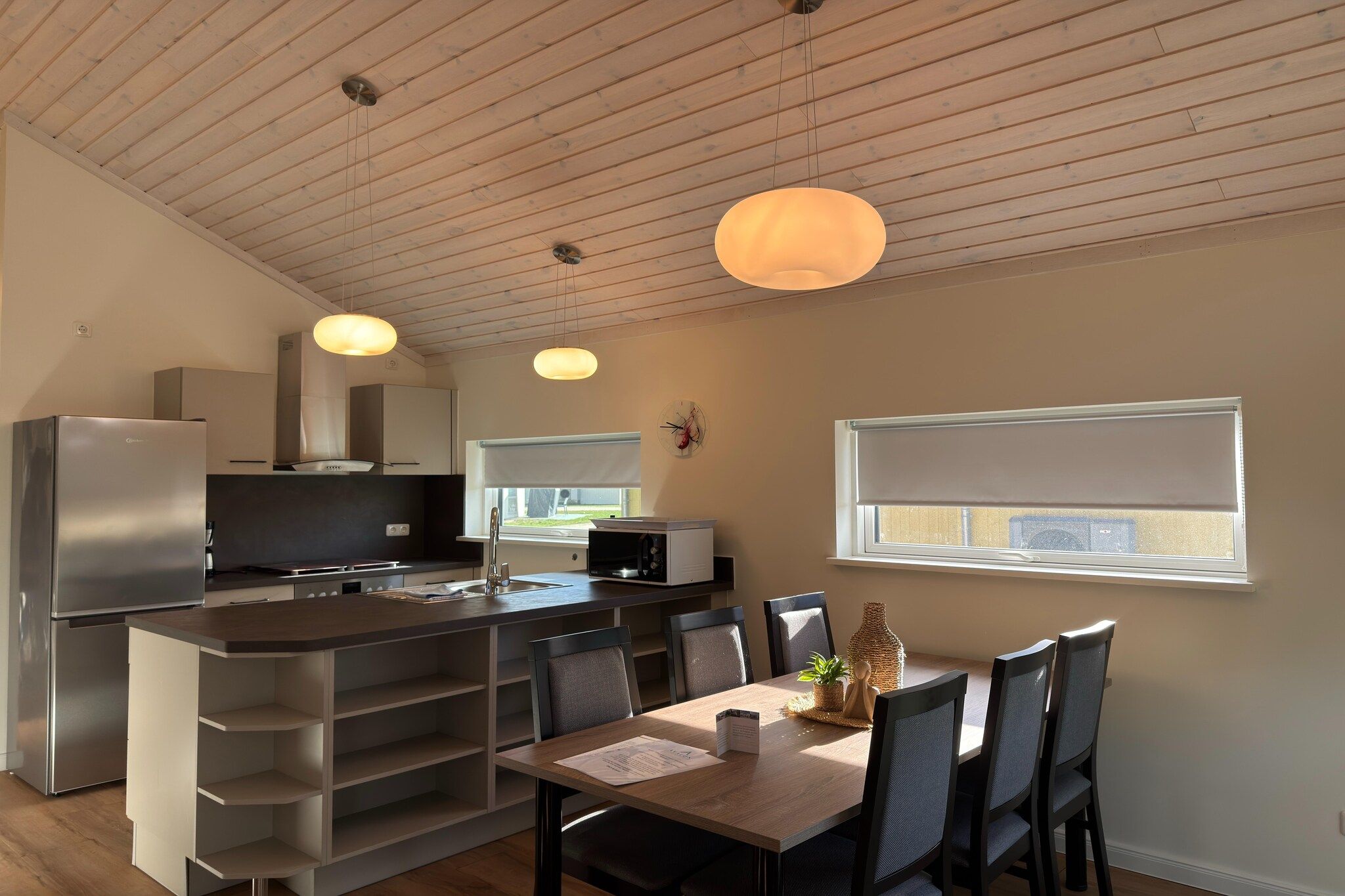 Une cuisine moderne avec un îlot central, un coin repas comprenant une table et des chaises, et une fenêtre offrant une belle vue.
