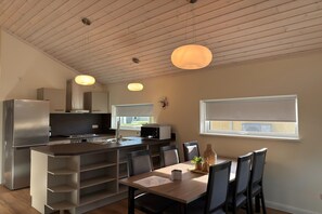 A modern kitchen with a central island, a dining area with a table and chairs, and a window with a view.