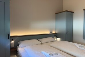 Ein Schlafzimmer mit Bett, Nachttischlampen, einem Kleiderschrank und einer Steckdose.