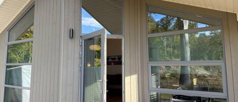 A modern house with large windows, a wooden deck, and a dining area.