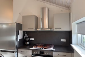 Una cocina moderna con electrodomésticos de acero inoxidable, horno empotrado y cafetera.