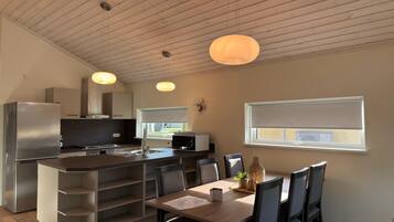 Une cuisine moderne avec un îlot central, un coin repas comprenant une table et des chaises, et une fenêtre offrant une belle vue.