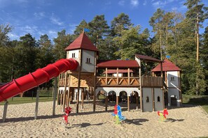 A playground with a red slide and wooden play structures. - Ferienhaus mit Whirlpool und Sauna in Bad Bevensen (Bad Bevensen)