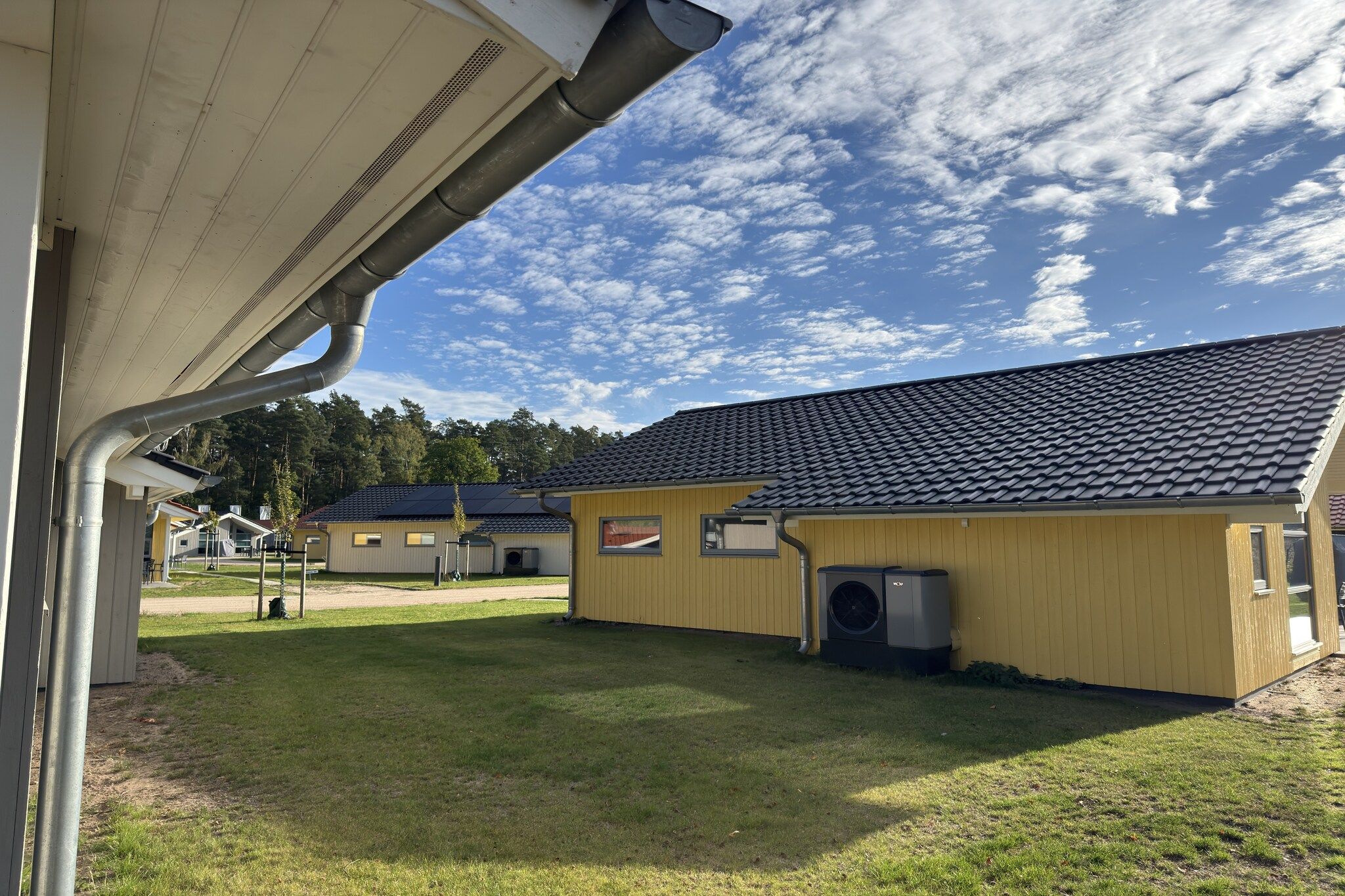 A building with a tiled roof, a covered outdoor area, and a grassy lawn.