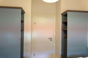 Een kamer met een gesloten deur, twee kasten en een lamp erboven.