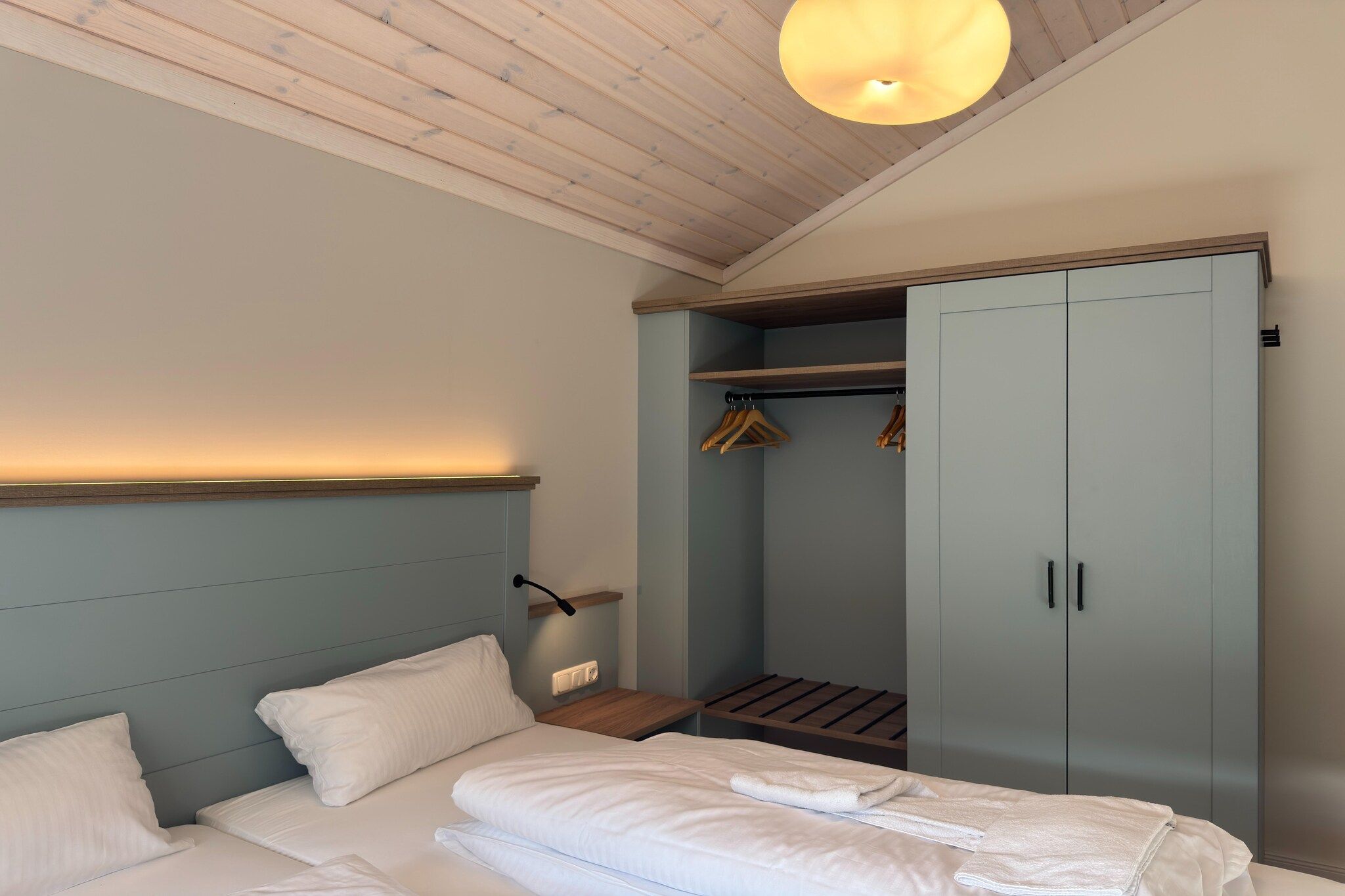 Ein Schlafzimmer mit einem Bett, Nachttischen, einem Kleiderschrank und einer Kleiderstange.