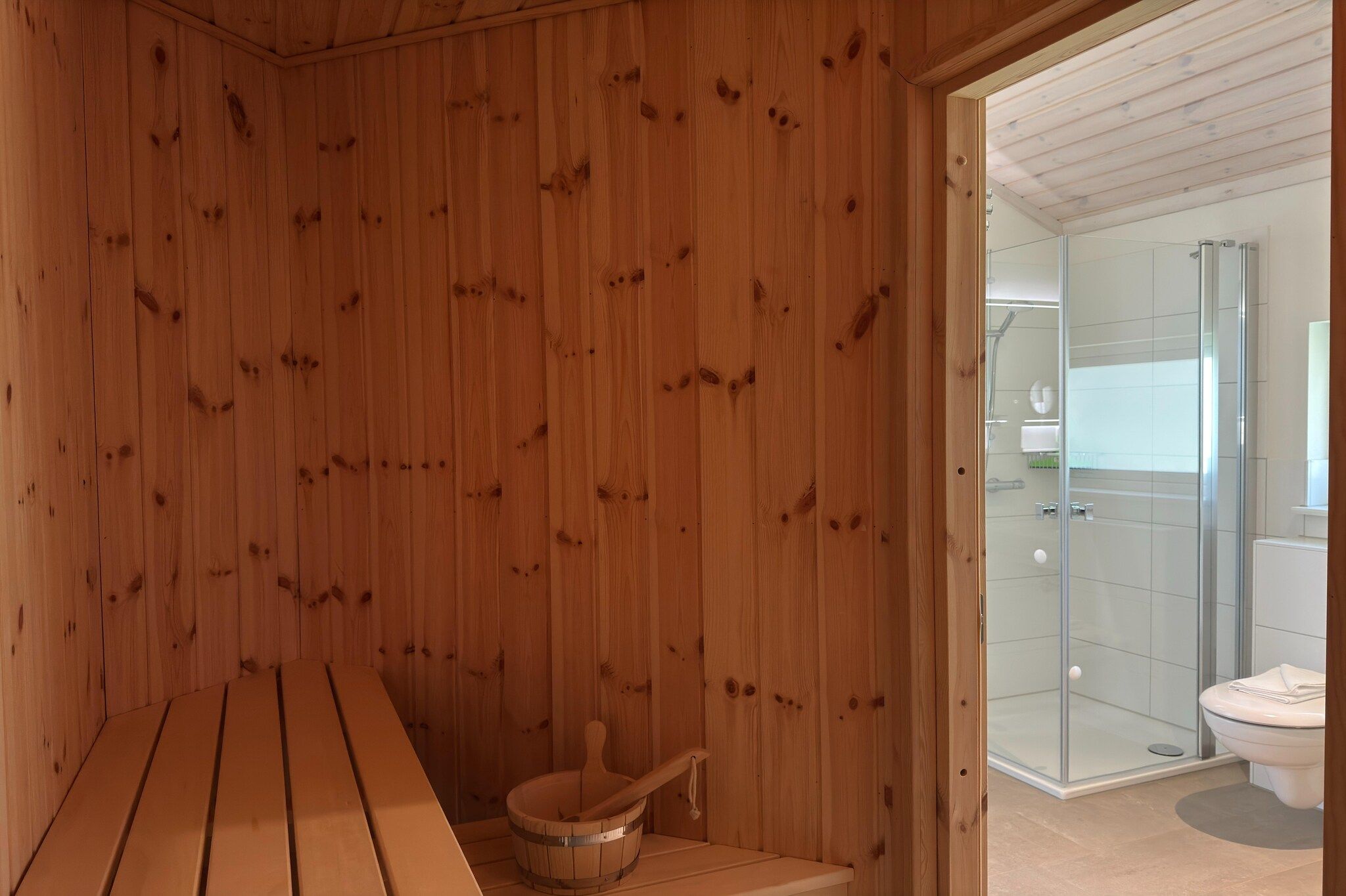 Un sauna avec des murs en bois, un banc et un seau en bois.