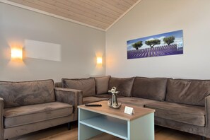 Een woonkamer met een bank, een salontafel en een schilderij aan de muur.