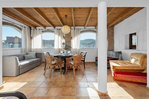 Un'ampia zona giorno con tavolo da pranzo, sedie, divano e un divano rosso.