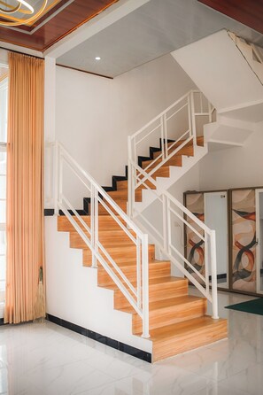 A modern staircase with wooden steps and white railings, leading to an upper floor.
