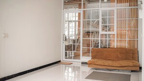 A room with a sofa, a sliding glass door, and a view of the interior. - Titik Damai Nexura Collection (Kejajar)