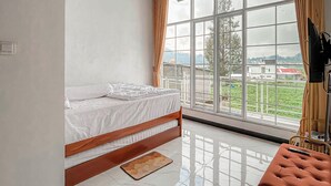 A bedroom with a bed, a window with a view, a ceiling with a light fixture, and a television. - Titik Damai Nexura Collection (Kejajar)