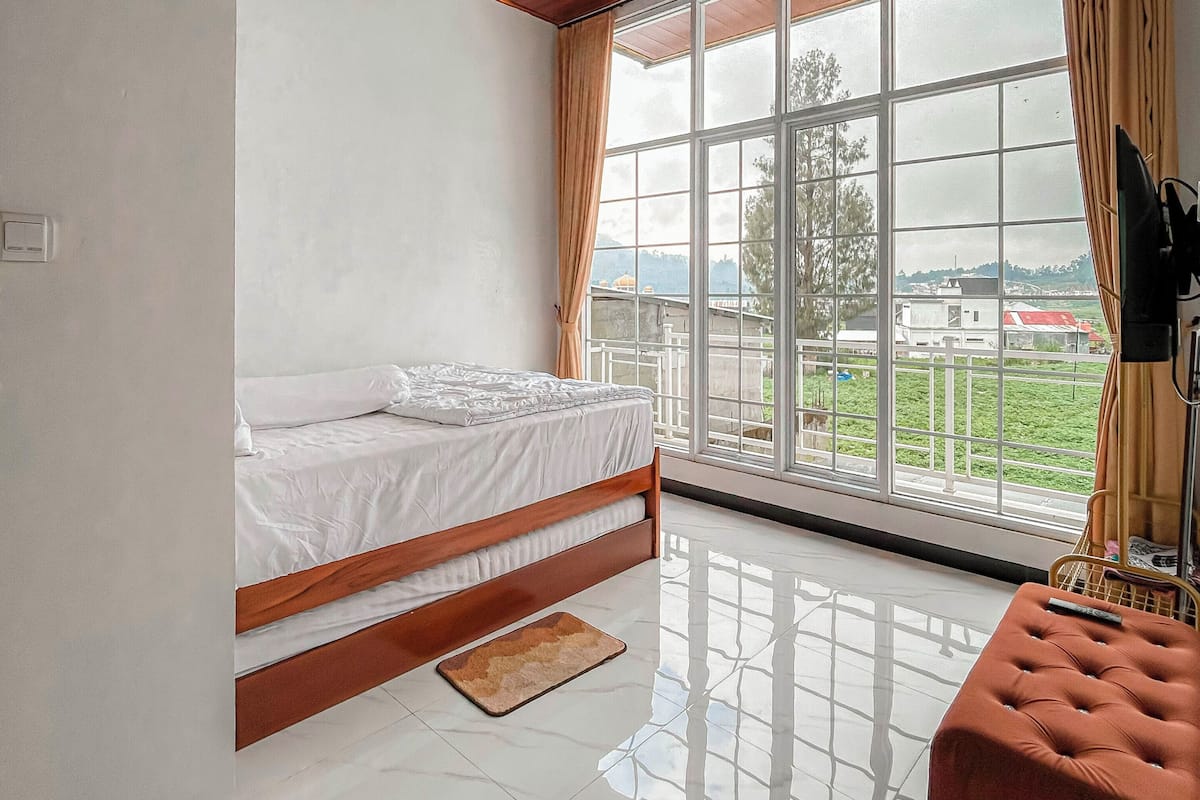 Un dormitorio con cama, ventana con vistas, techo con lámpara y televisor.