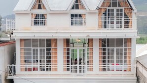 Ein mehrstöckiges Gebäude mit großen Fenstern, einem Balkon und einem geparkten Auto davor.