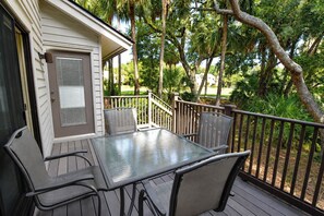 Eine Terrasse mit Tisch und Stühlen, umgeben von einem Holzgeländer und Bäumen.
