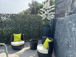 Outdoor seating with wicker chairs and cushions, a potted plant, and a stone wall. - Beautiful Villa Near Etna and see (Trecastagni)