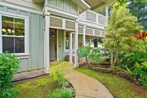 Ein Haus mit Veranda, Weg und verschiedenen Pflanzen.