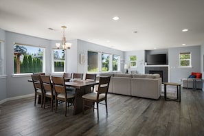 A spacious living area with a dining table, chairs, a sofa, and a television. - Blaine Breezes by Gather: Coastal Home w/ Backyard, Beach Access & A/C (Blaine)