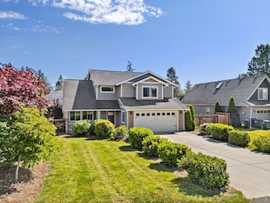 A two-story house with a garage, surrounded by well-maintained lawns and bushes.
