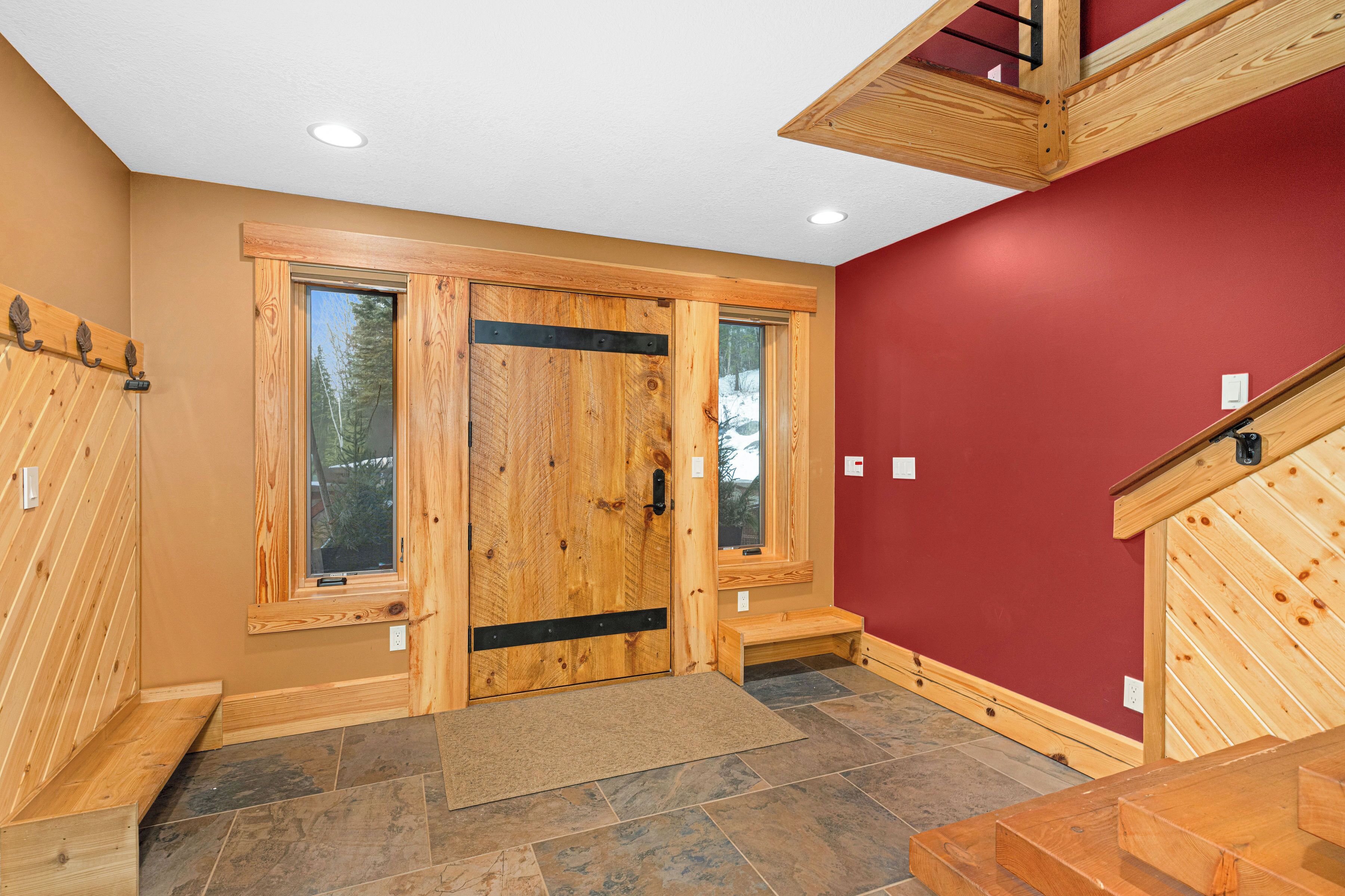 A wooden interior with a red wall, a wooden door with a window, and a bench.