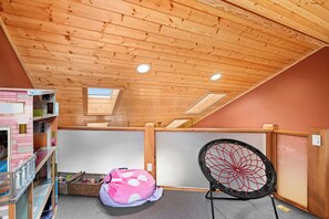 A room with a sloped ceiling, wooden beams, a pink bean bag, a spider web decoration, and a small window. - Panoramic Views of Lake Superior! Eagle Mountain Lodge at Lutsen (Lutsen)