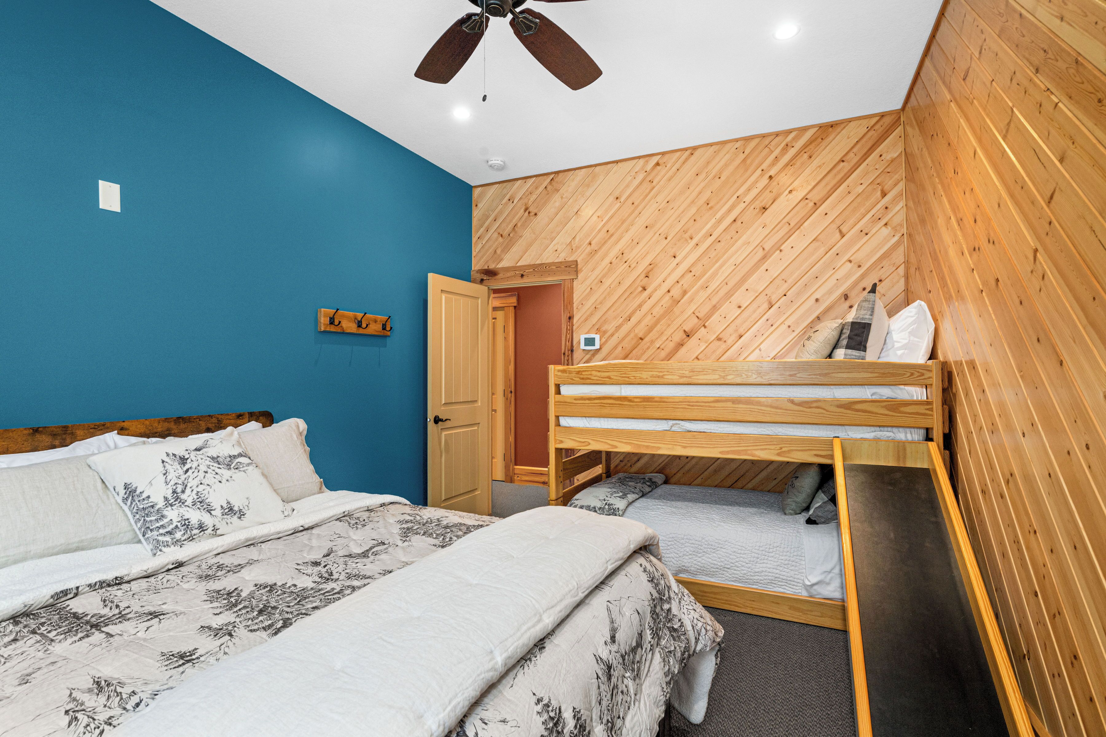 Un dormitorio con una cama litera, una pared de madera y un ventilador de techo.
