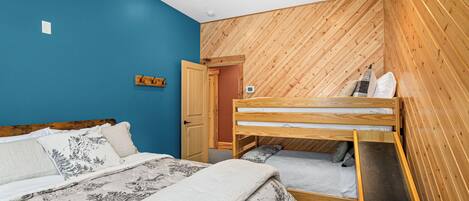 Un dormitorio con una cama litera, una pared de madera y un ventilador de techo.