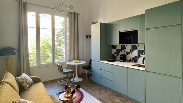 Una sala de estar moderna con un sofá, una mesa de centro y una zona de cocina con armarios y una encimera.