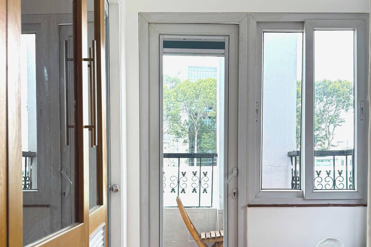 A room with a bed, a chair, a window, and a door.