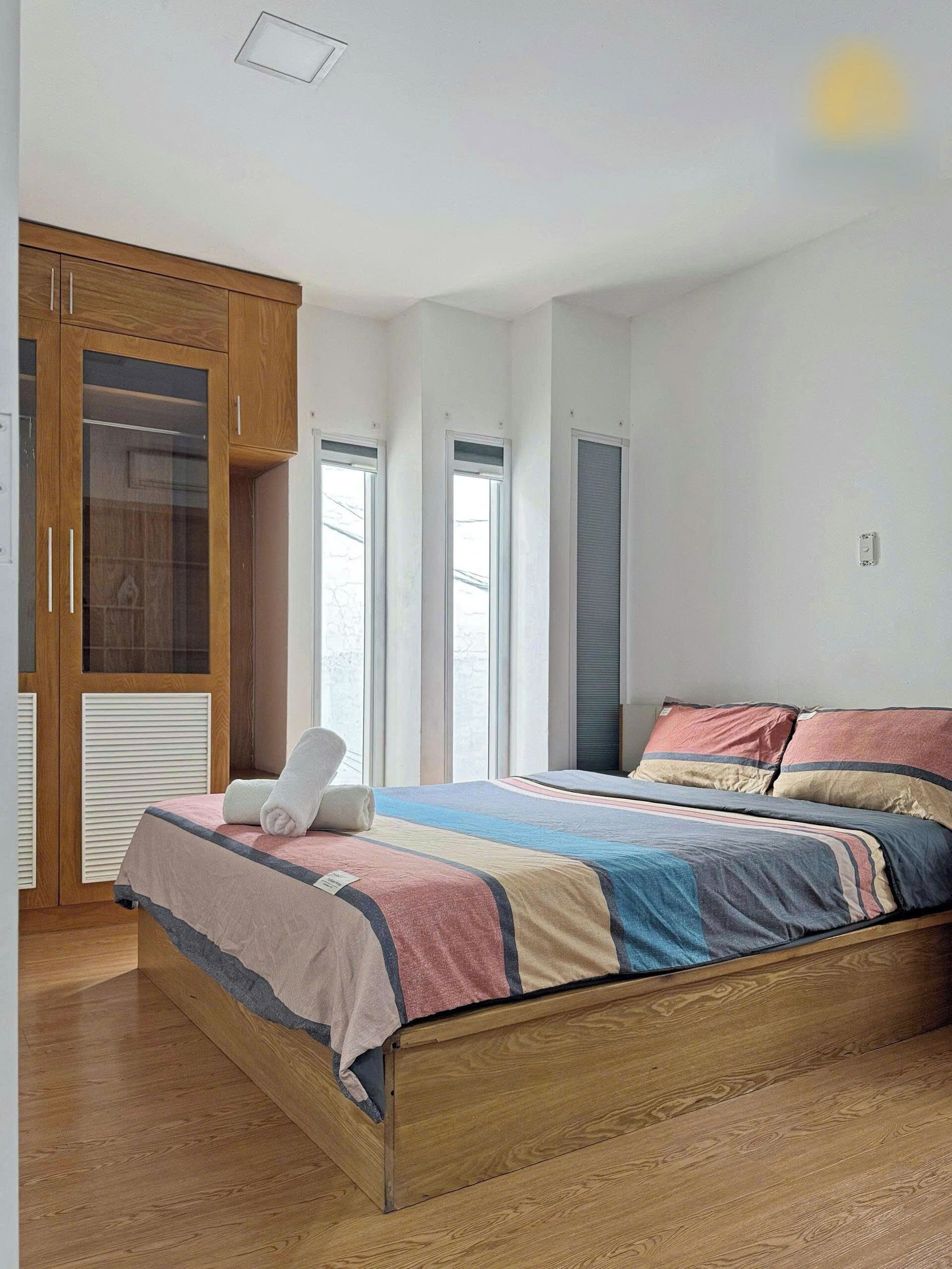 Un dormitorio con una cama de madera, un armario y una ventana.