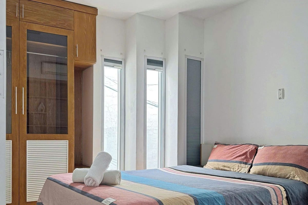 A bedroom with a wooden bed, a large wardrobe, and a window.