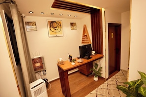 A room with a wooden desk, a television, a potted plant, and a door. - Standard Double Room #1 (Giza)