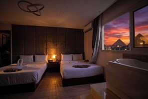 A hotel room with two beds, a large window with a sunset view, a bathtub, and a modern light fixture. - Standard Double Room #1 (Giza)
