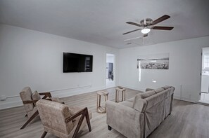 Ein modernes Wohnzimmer mit Flachbildfernseher, Deckenventilator, Sofa und Couchtisch.