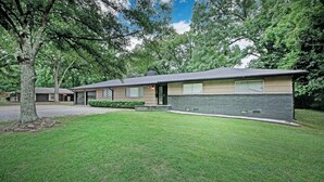 A modern two-story house with a stone facade, a garage, and a well-maintained lawn. - 7BR Workforce Stay Near I-55 & I-220 (Jackson)