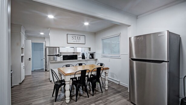 A modern kitchen with a stainless steel refrigerator, a dining table with chairs, and a microwave. - 7BR Workforce Stay Near I-55 & I-220 (Jackson)