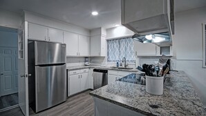A modern kitchen with white cabinets, stainless steel appliances, and granite countertops. - 7BR Workforce Stay Near I-55 & I-220 (Jackson)